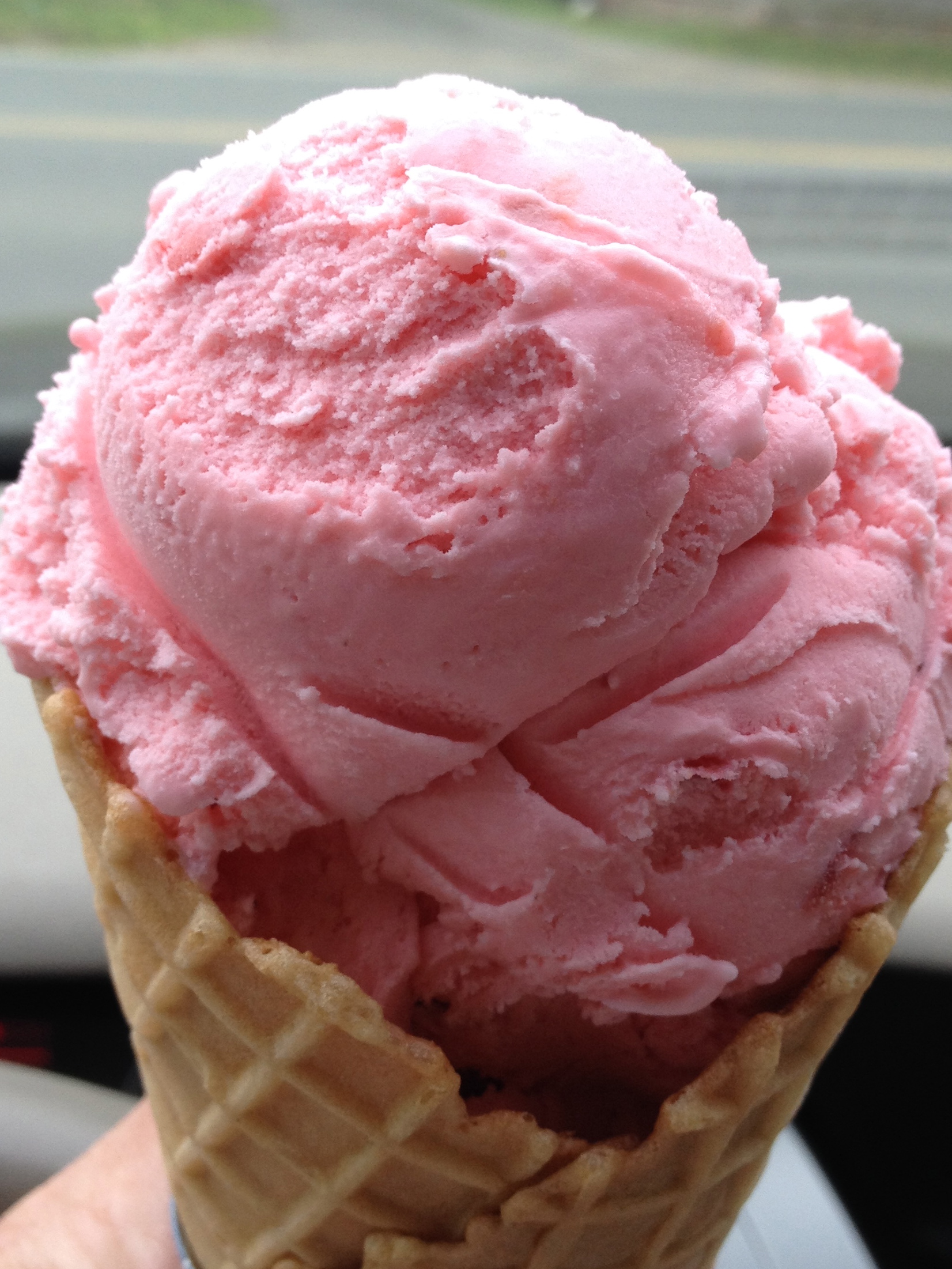 Pink ice cream in a waffle cone.